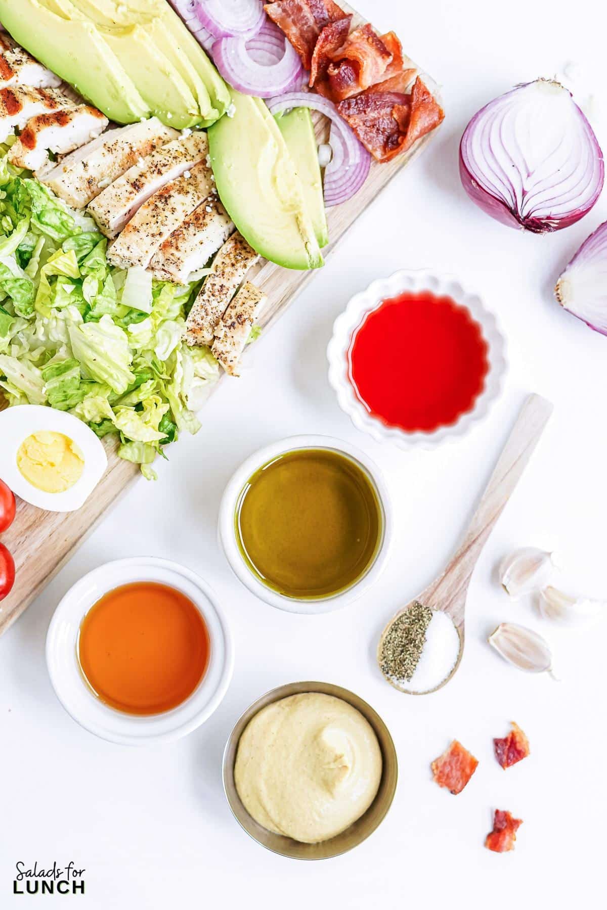 Classic cobb salad dressing ingredients in little bowls: Extra virgin olive oil, red wine vinegar, honey, dijon mustard, garlic, salt and pepper.