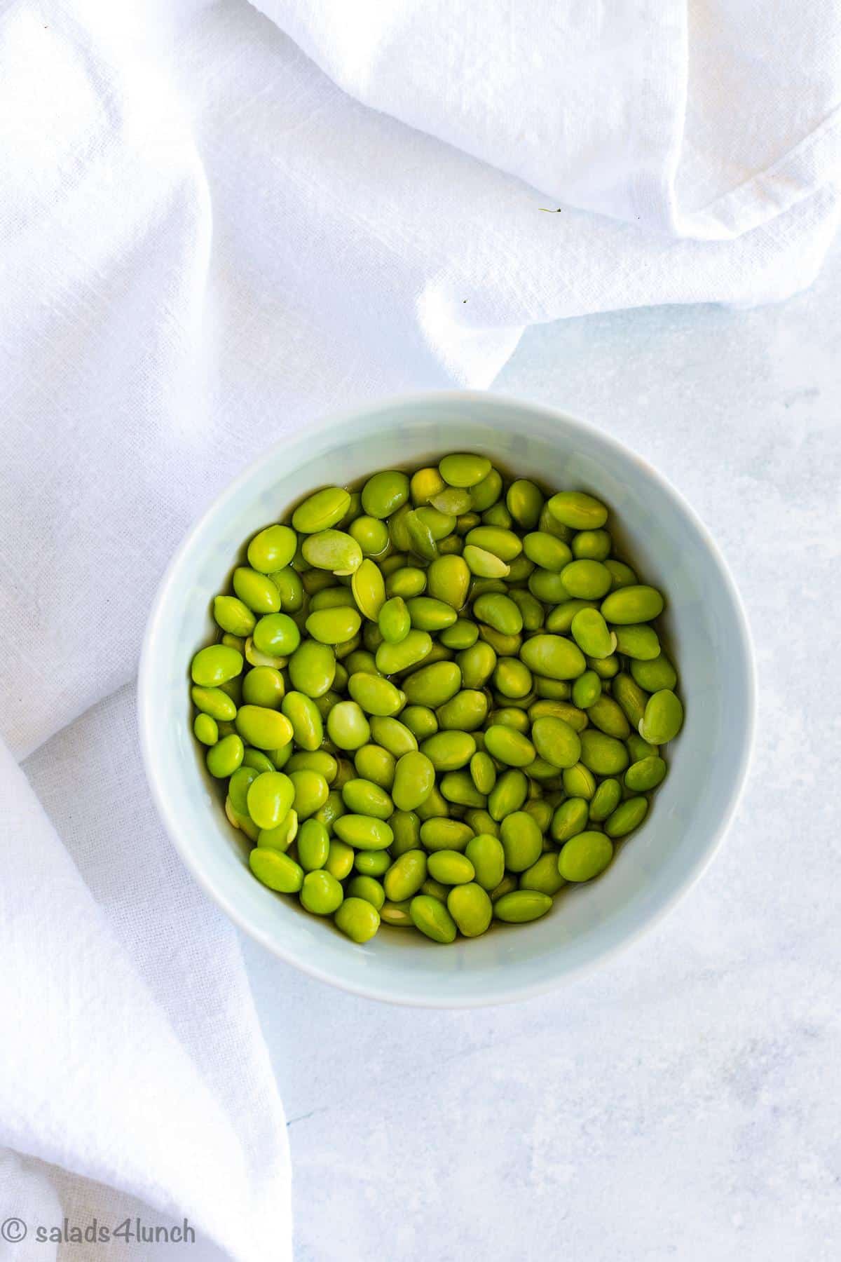 White bowl full of edamame.