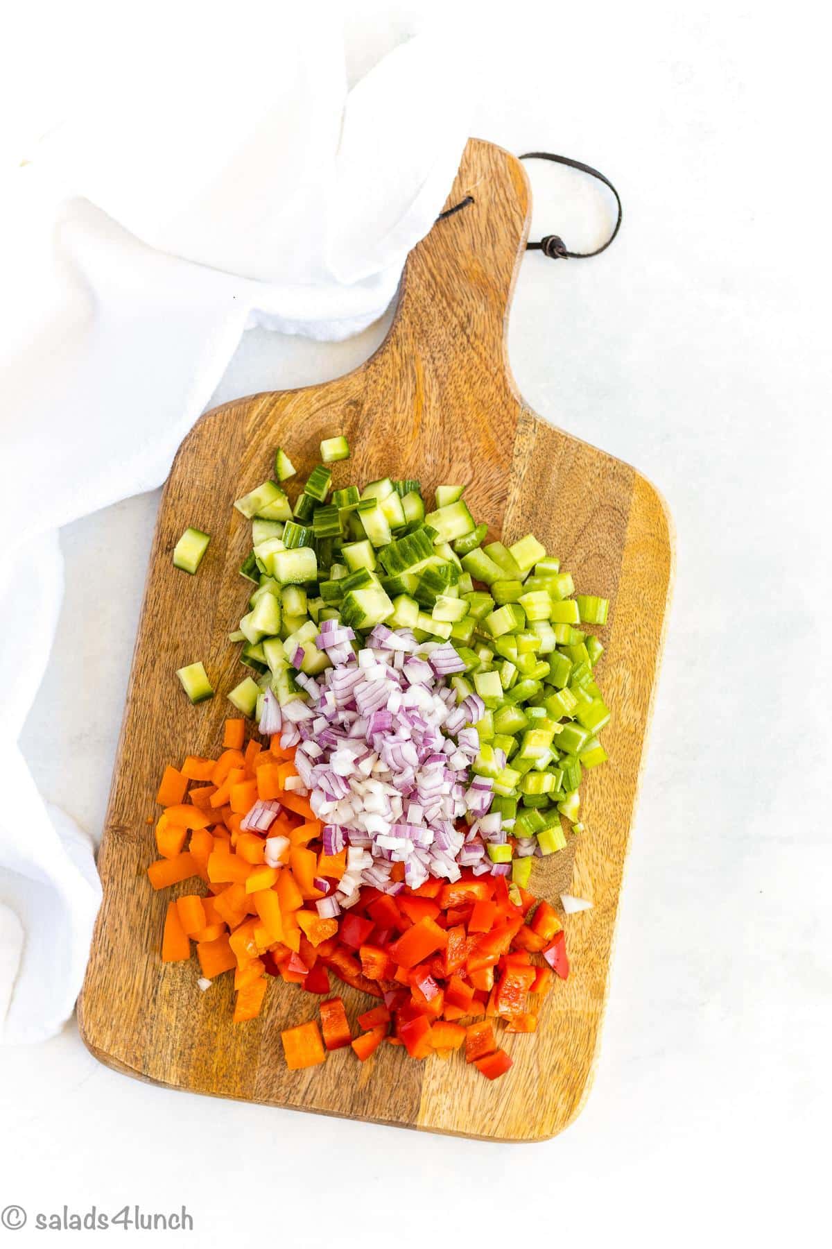 Chopped veggies for basmati rice salad on a wooden cutting board.