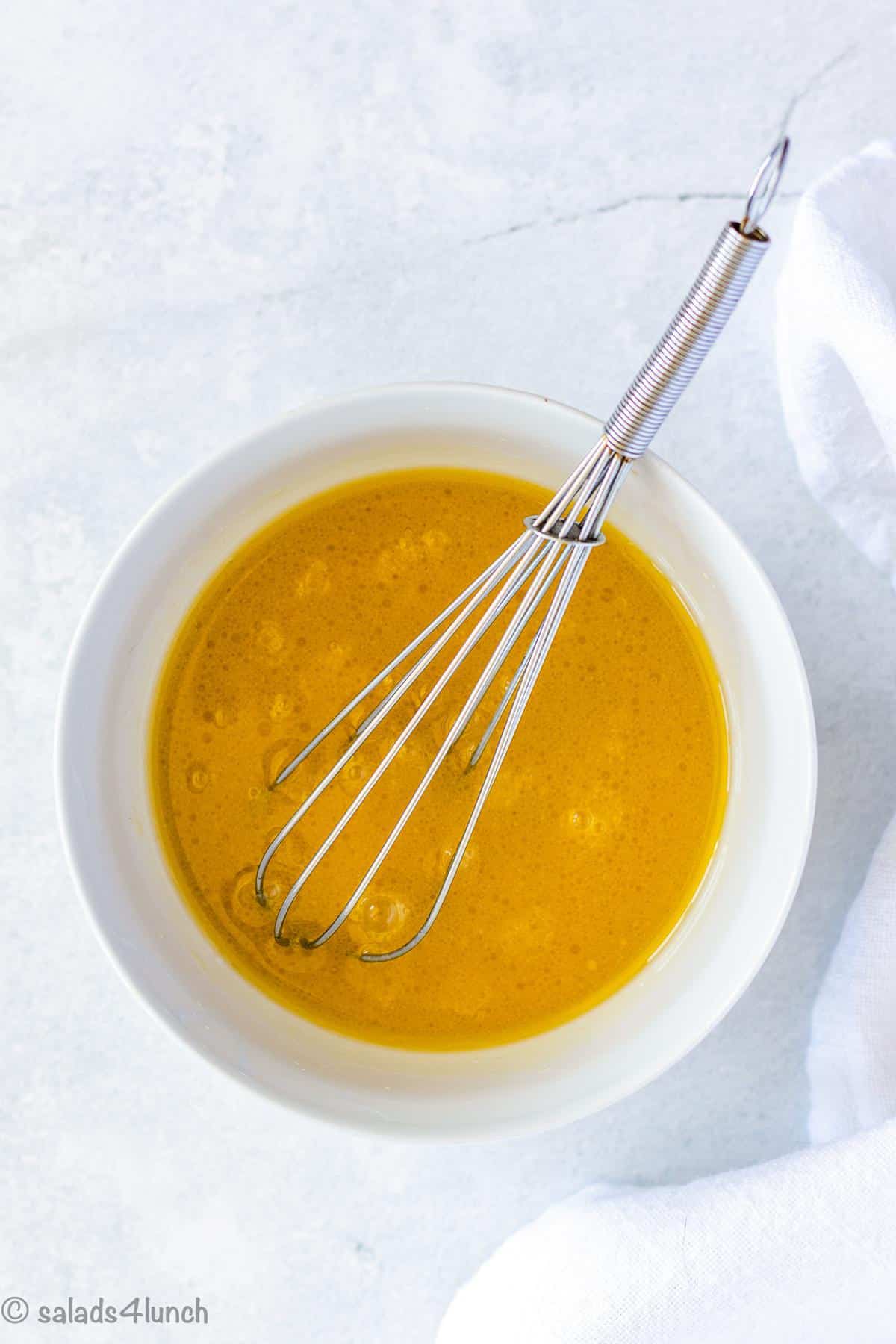 Basmati rice salad dressing in a white bowl with a whisk.