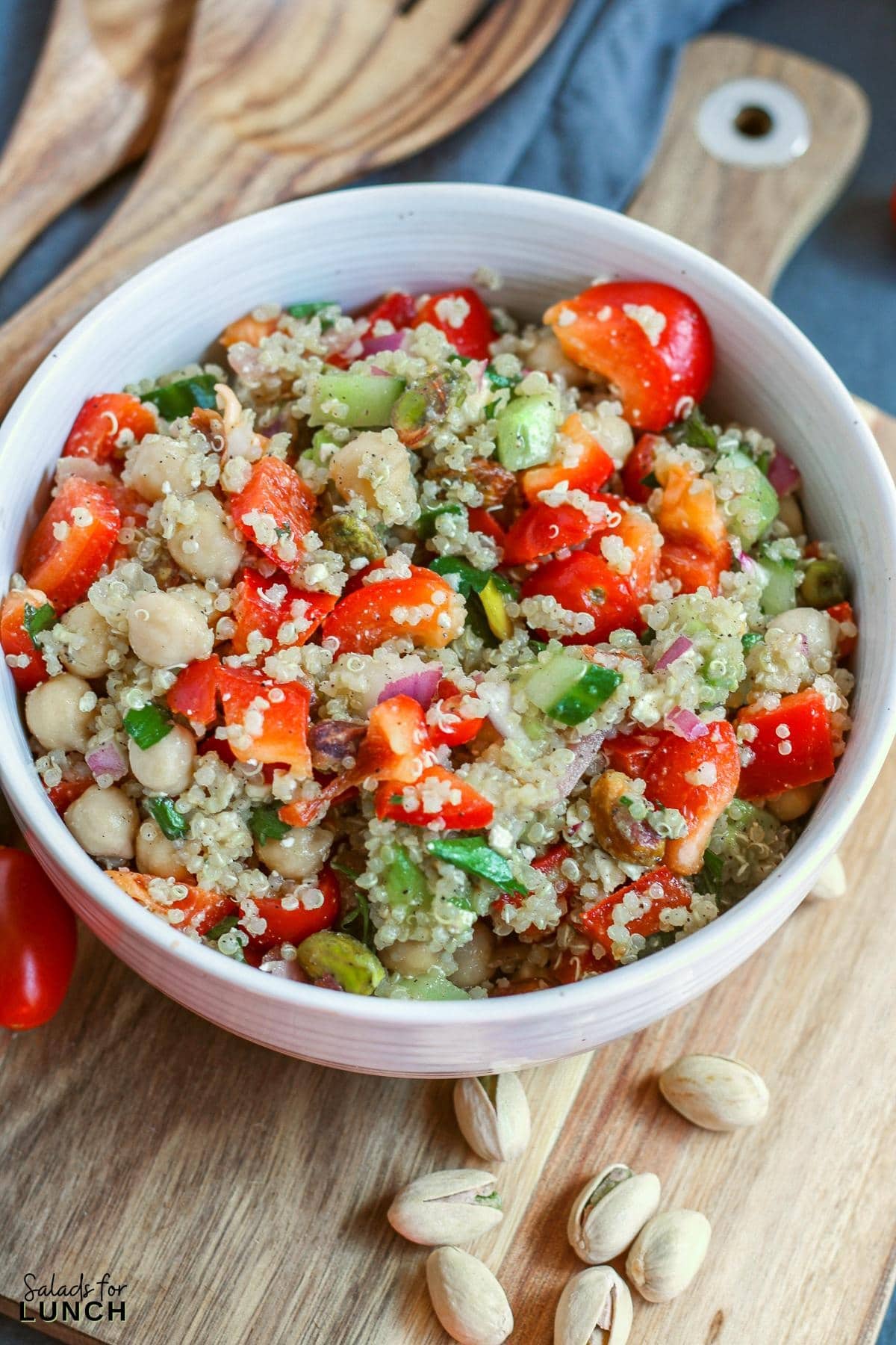 Close up of a very colourful quinoa salad in a white bowl on a cutting board.