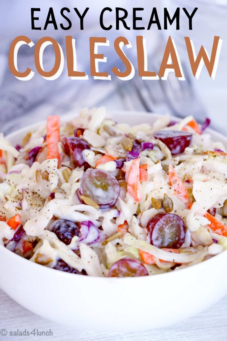 Close up of the best ever creamy coleslaw recipe with grapes in a white bowl on a white wooden table. 