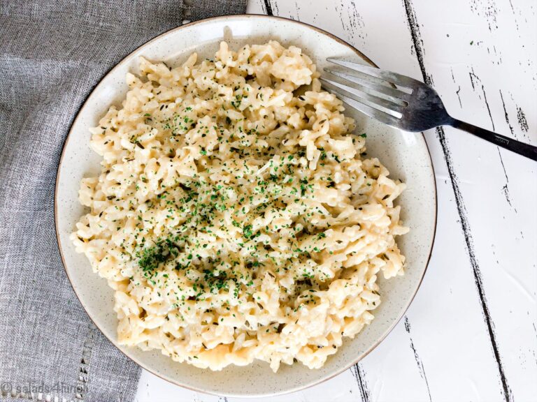 Photo showing close up of plate with Instant Pot Creamy Garlic Parmesan Risotto on a white background with a light grey napkin