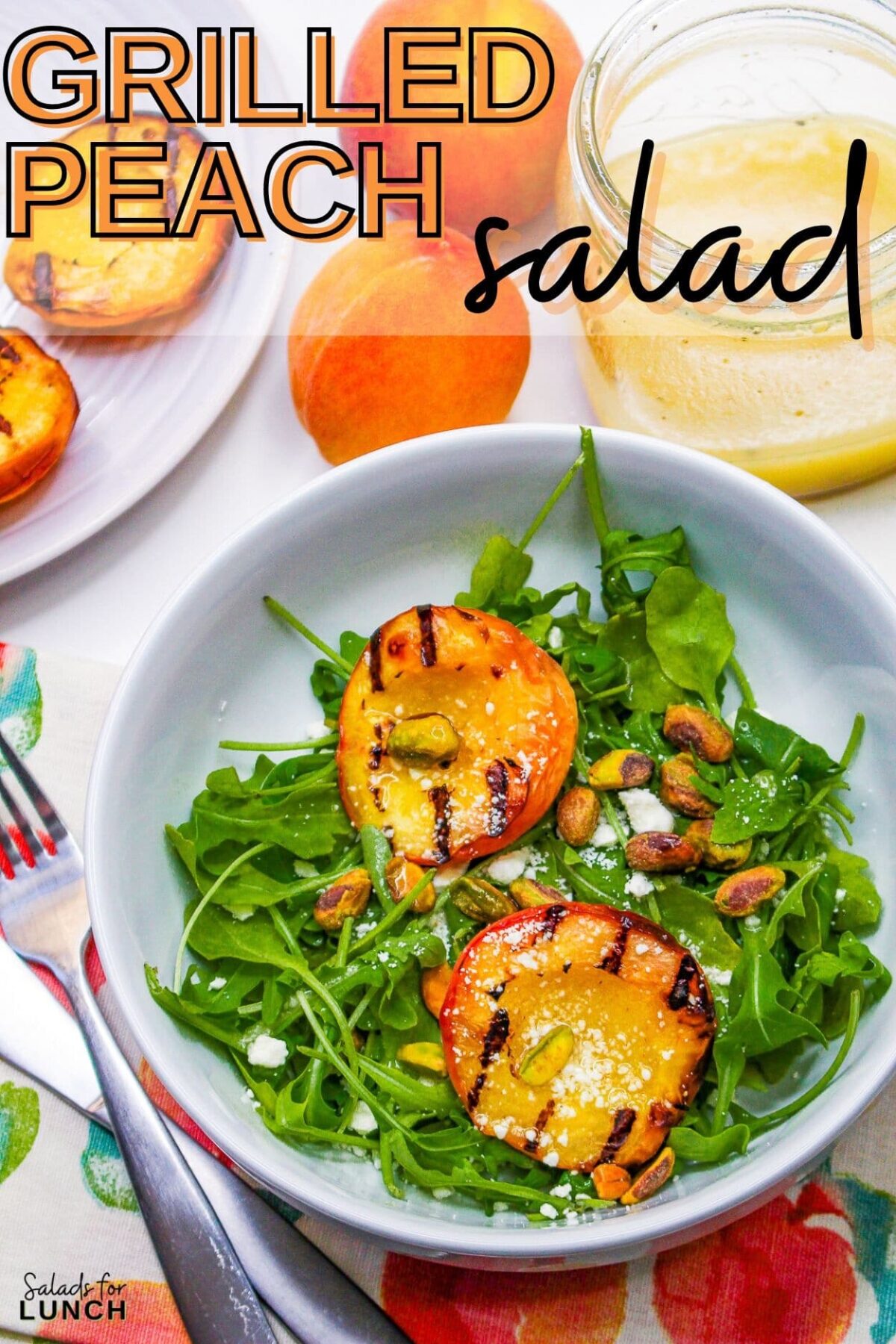 Grilled peaches summer salad in a white bowl with arugula and pistachios.