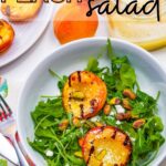 Grilled peaches summer salad in a white bowl with arugula and pistachios.