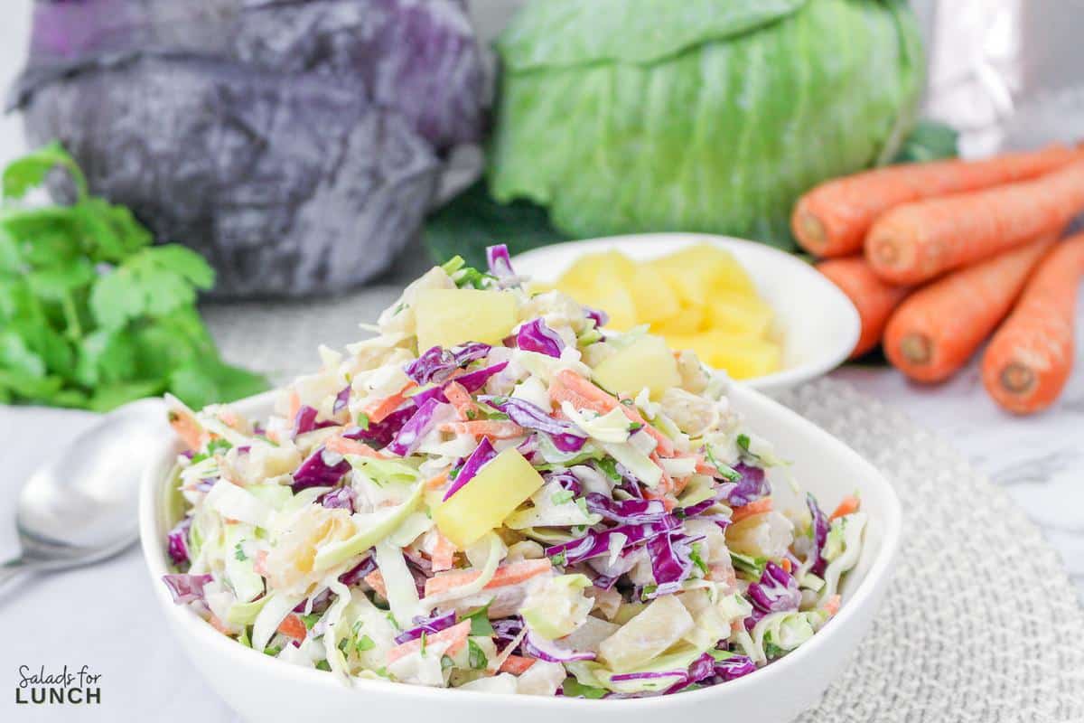 Close up of Hawaiian inspired coleslaw with red and green cabbage and carrots in the background.