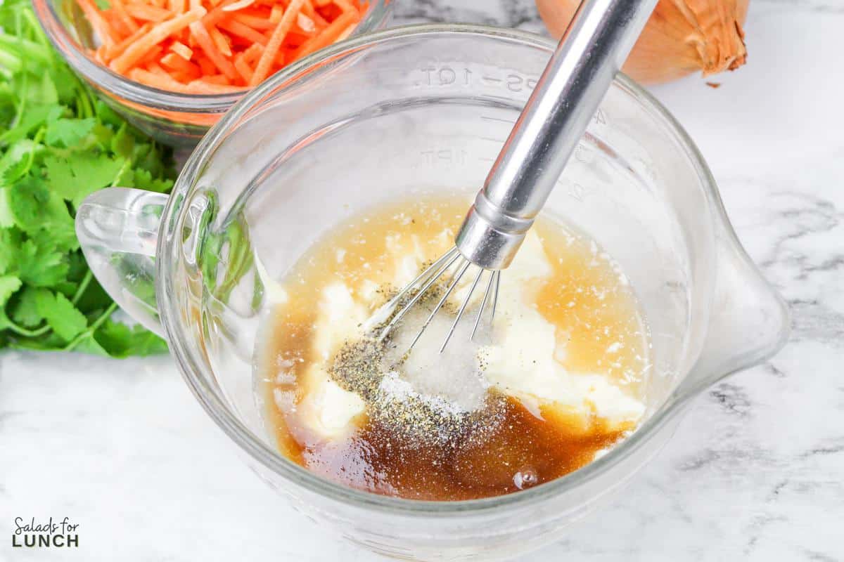 Coleslaw dressing ingredients in a clear glass mixing bowl.