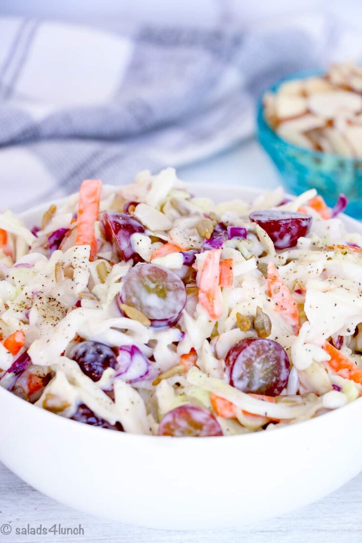 Creamy Coleslaw in a white bowl with grapes and sunflower seeds with text overlay that says: "Easy Creamy Coleslaw".
