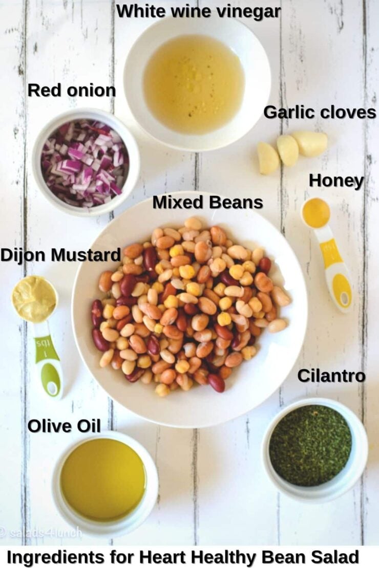 Overhead photo of ingredients needed to make bean salad: mixed beans, cilantro, red onion, dijon mustard, white wine vinegar, honey, and olive oil.