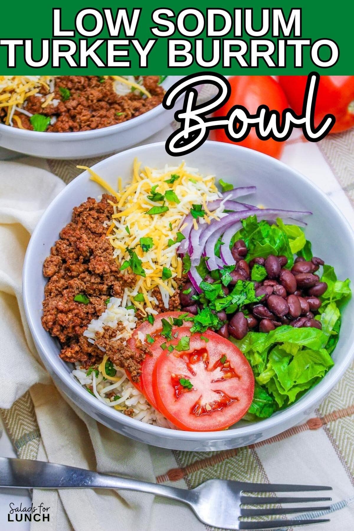 Image of a Low Sodium Ground Turkey Burrito Bowl Salad in a white bowl. The bowl is filled with a colorful mixture of cooked brown rice, seasoned ground turkey, black beans, diced tomatoes, sliced red onions, shredded lettuce, and taco blend cheese. A dollop of guacamole and a sprinkling of fresh cilantro top the vibrant ingredients.
