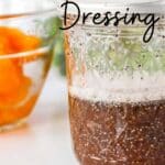 Close up of a mason jar with orange poppy seed dressing in it and mandarin orange slices in a bowl in the background.