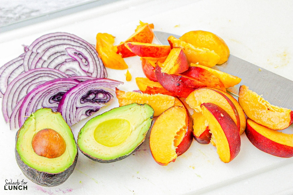 Peach, red onion and avocado slices on a white plate.