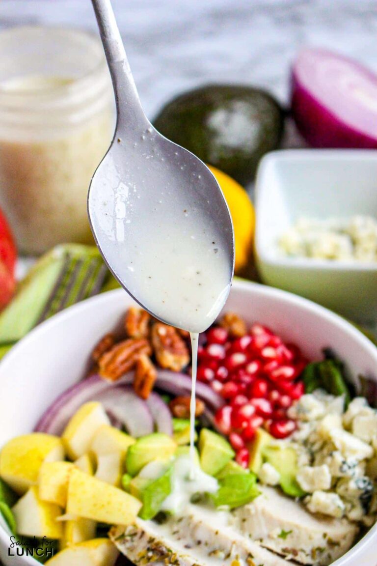 Gorgonzola salad dressing dripping from a spoon onto a fresh and delicious pear salad with pomegranates, candied pecans, red onion, avocado, left over turkey and spring mix.