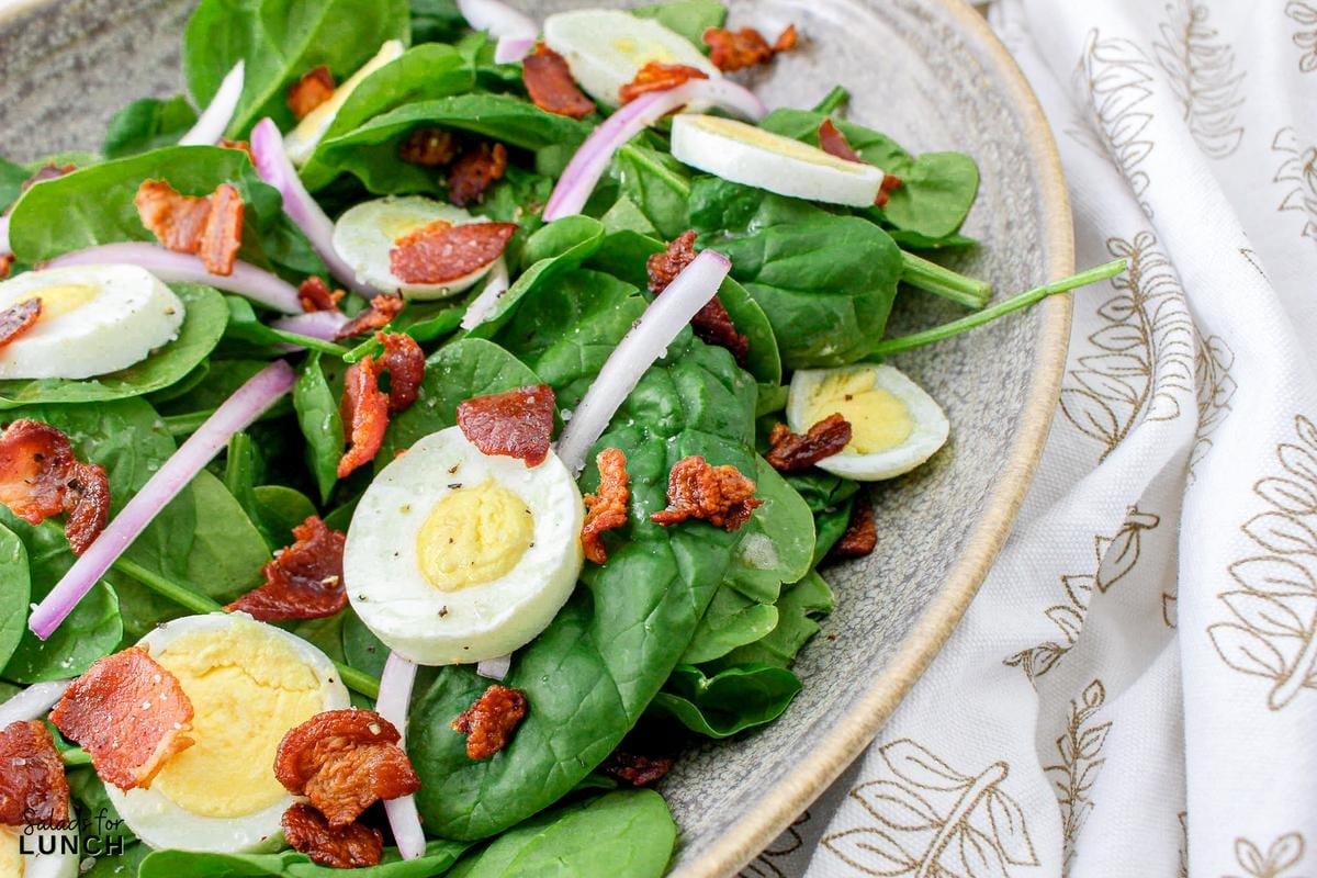 Spinach Salad with Eggs and Bacon Recipe 13 - Crisp baby spinach leaves, creamy hard-boiled eggs, savory bacon crumbles, and tangy red onion come together in perfect harmony, topped with a drizzle of homemade red wine vinegar dressing. It’s a satisfying spinach, egg and bacnon salad that’s as easy to make as it is delicious to eat!