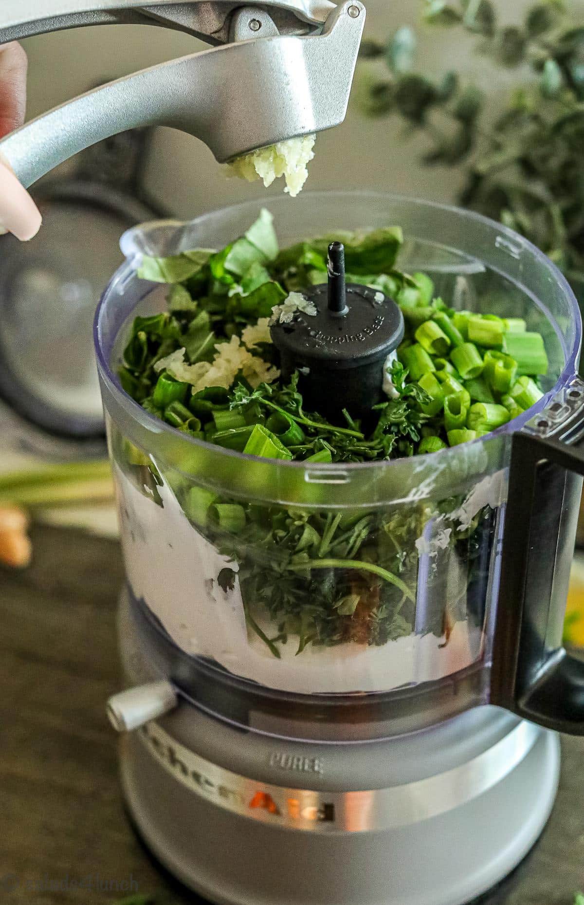 Step 1 of green goddess dressing, crushed garlic being added to food processor.