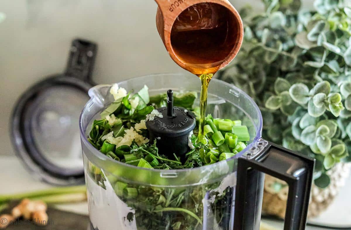 Step 2 of green goddess dressing, olive oil being added to food processor.