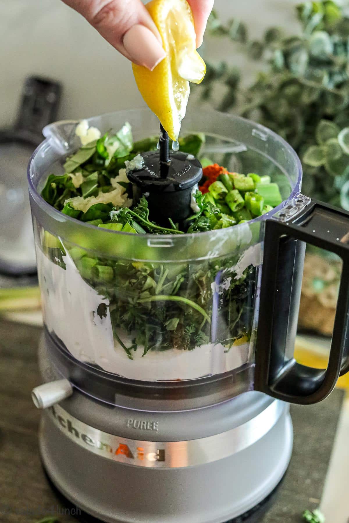 Step 1 of green goddess dressing, fresh squeezed lemon juice being added to food processor.