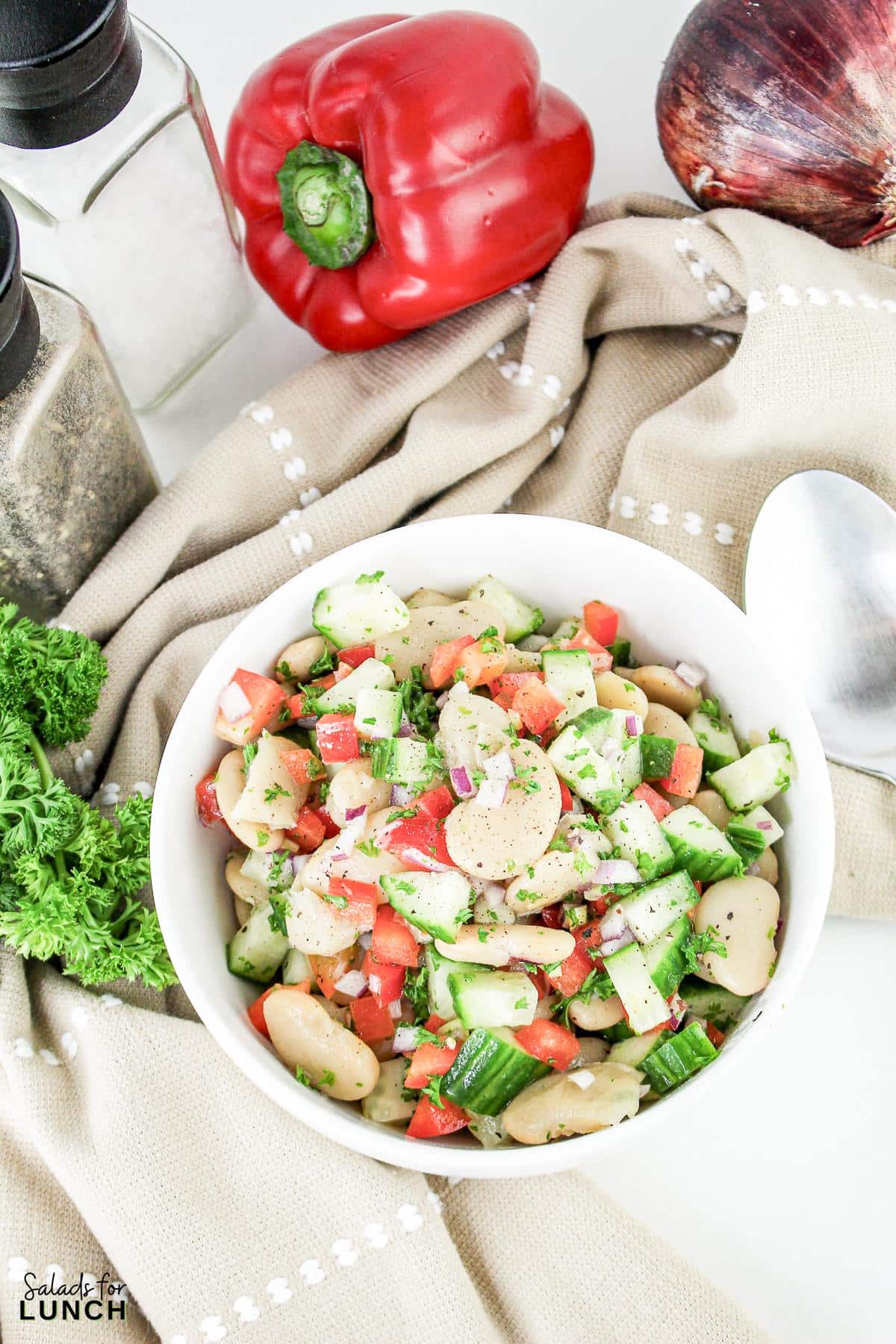 A bowl of Butter Bean salad with vegetables and a spoon.