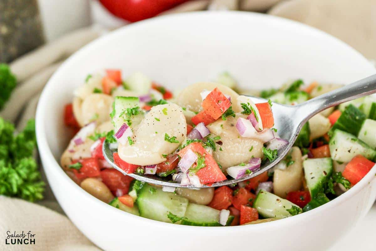 Close up of a bowl of Summer Butter Bean salad with a spoon.