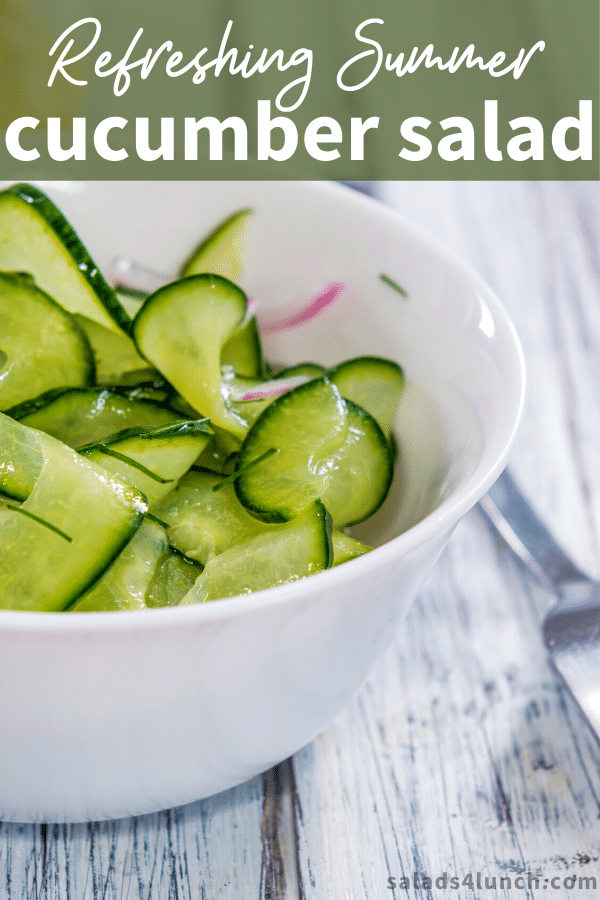 Spiralized cucumber salad with vinegar in a white bowl on a white washed wooden counter.